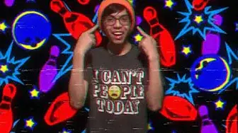 person wearing an orange beanie pointing at their face in front of a colorful background