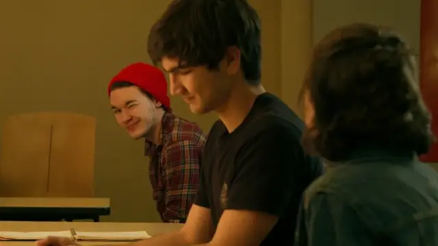 boy with a red beanie smirking behind a boy with dark hair