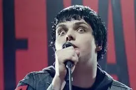 picture of boy with dark hair holding a microphone staring intensely at camera